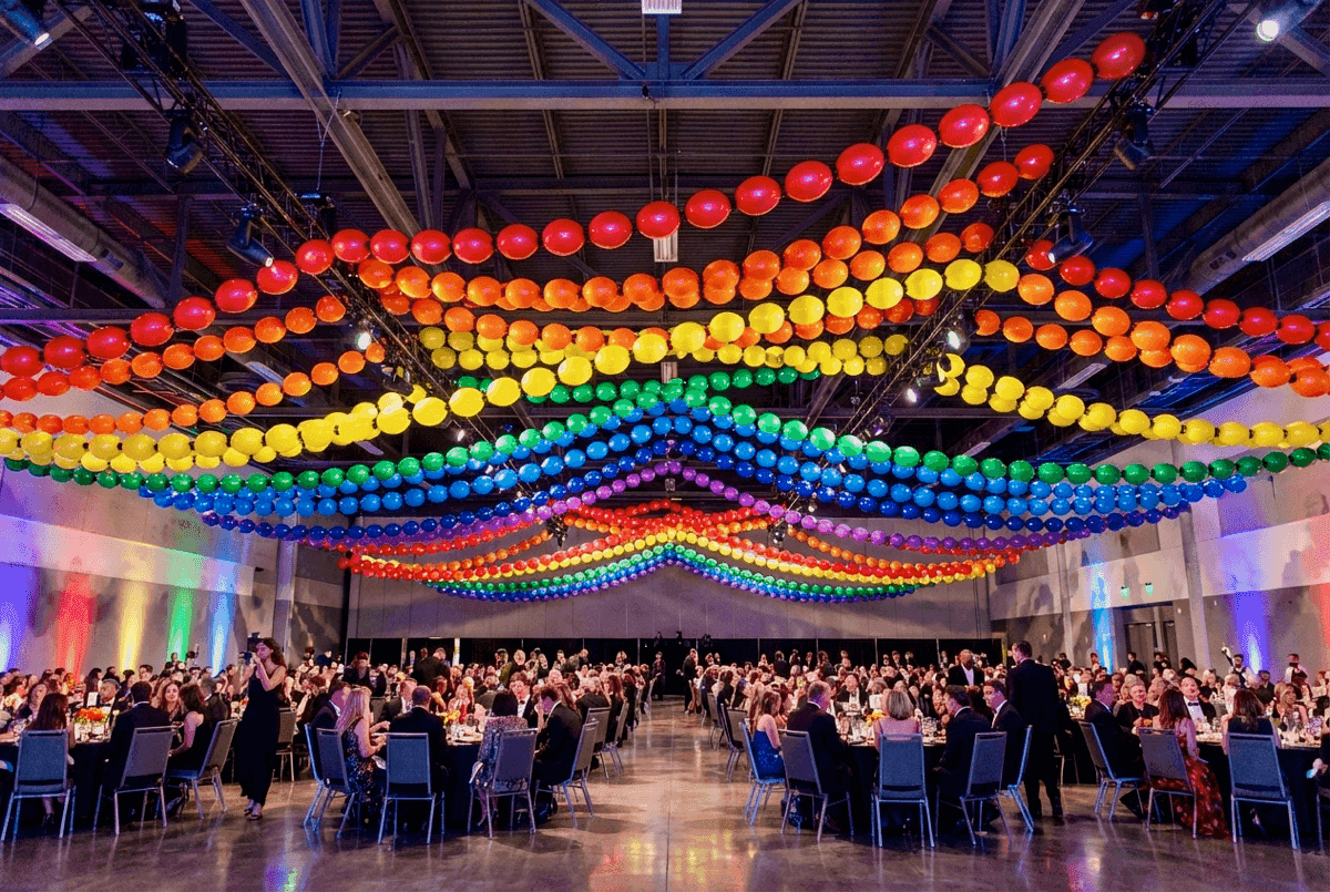 Lange Regenbogen-Ballongirlande über einem Festivalgelände