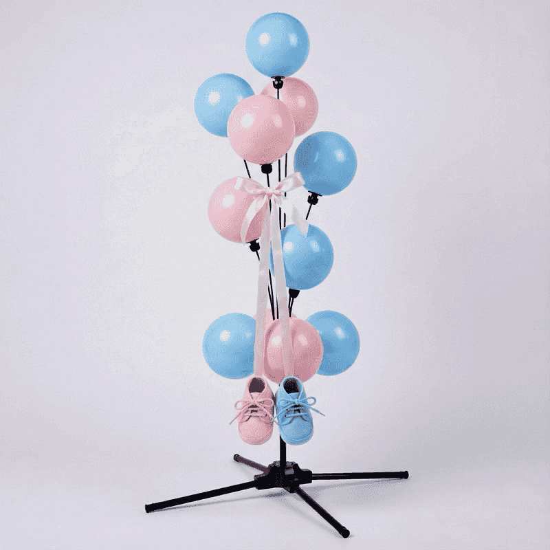 Süße Gender Reveal Ballonfontäne mit rosa und blauen Babyschuhen hängend an goldenen Bändern zwischen den Ballons